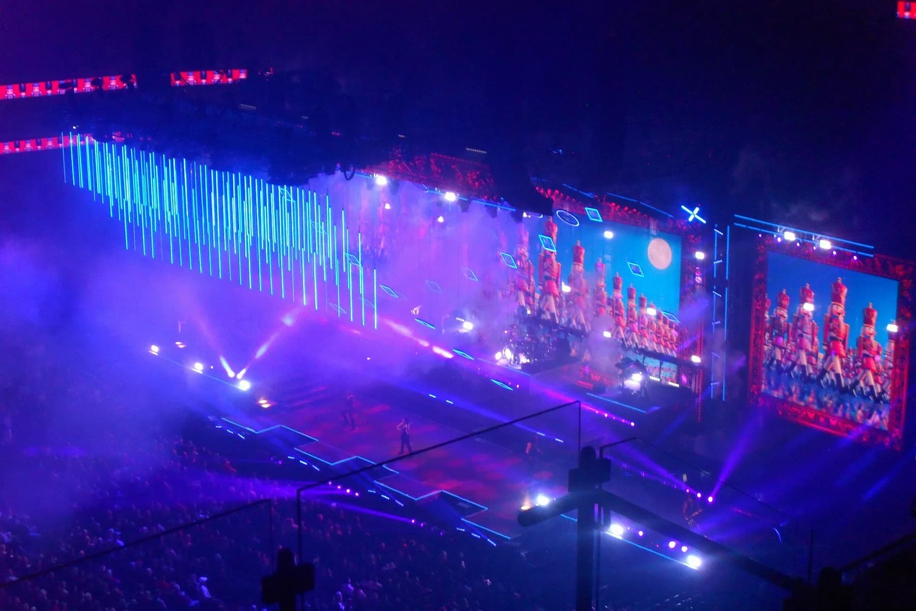 Escenario de concierto con grandes pantallas LED y visuales azules y violetas